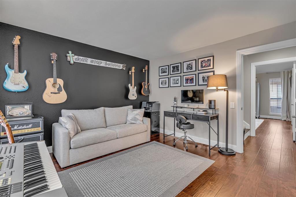 Second Bedroom. Dark accent wall, light-toned wall paint, wood-finish flooring, white baseboards, and a doorway with trim