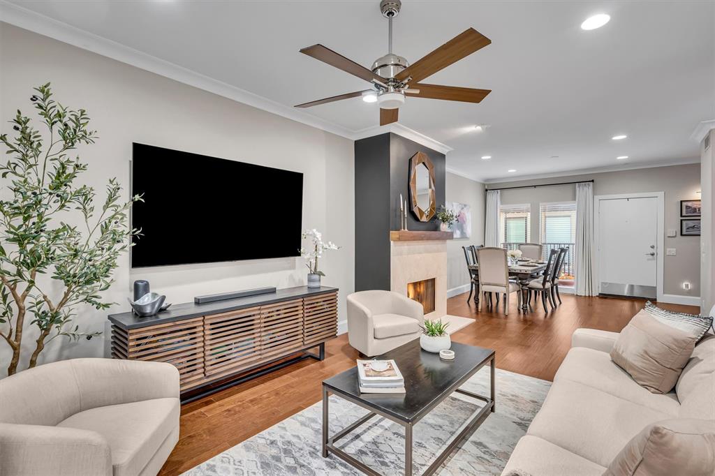 Hardwood-finish flooring, recessed lighting, crown molding, and a built-in fireplace with a stone surround