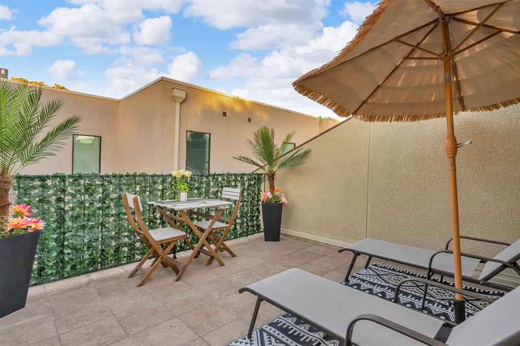 Outdoor patio space with tile flooring, privacy screening, and stucco exterior walls