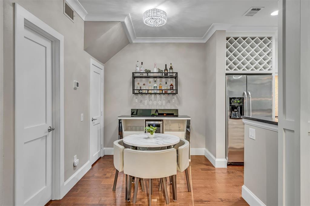 Hardwood-style flooring, crown molding, built-in wine rack, and stainless steel refrigerator