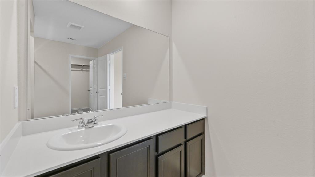 Vanity with a white countertop, undermount sink, and dark wood-finish cabinetry