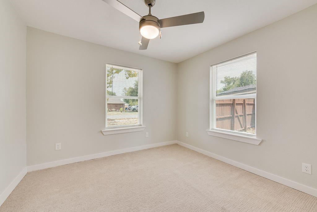 Neutral wall finishes, dual window placements, ceiling fan with integrated lighting, and carpeted flooring
