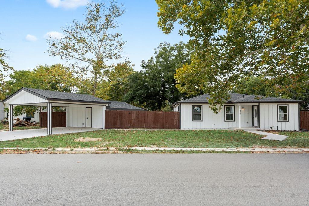 White vertical siding exterior with black trim windows, a covered front entry, and a dedicated carport