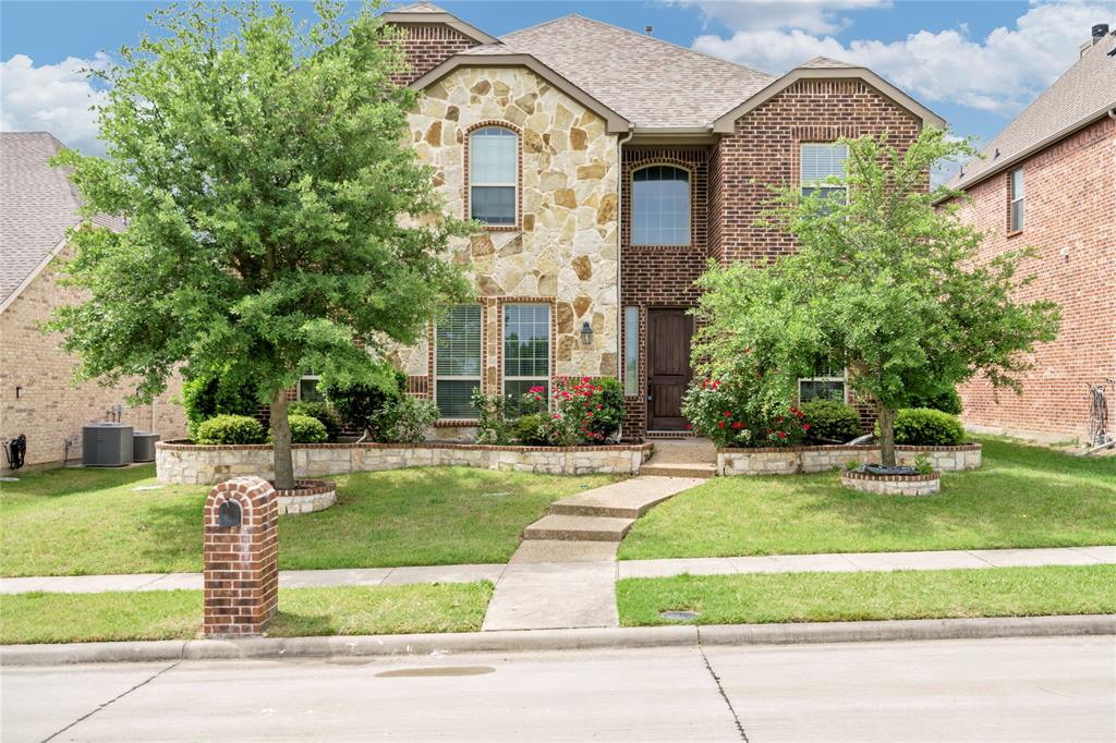 Brick and stone exterior with arched windows, a multi-level roofline, and established landscaping Brick and stone exterior with arched windows, a multi-level roofline, and established landscaping