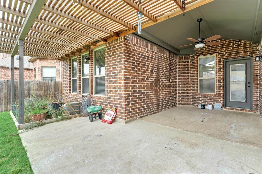 Covered patio featuring a ceiling fan, brick exterior, and wood lattice pergola