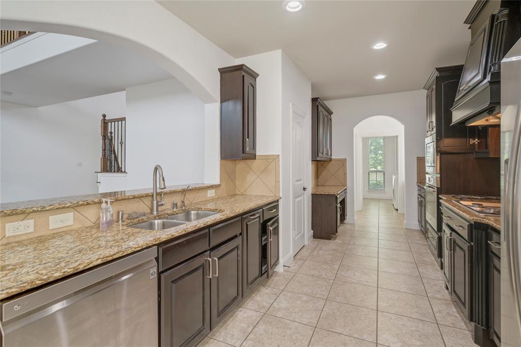 Kitchen featuring dark wood cabinetry, light granite countertops, stainless steel appliances, a tile backsplash, and recessed lighting