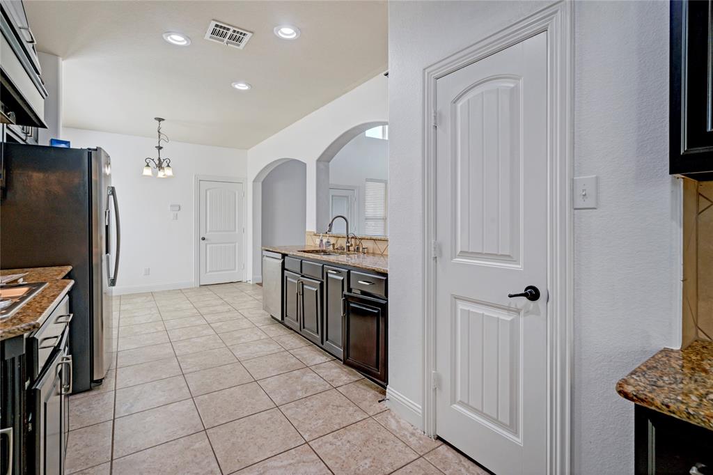 Kitchen with tile flooring, recessed lighting, arched doorways, a built-in dishwasher, and granite countertops