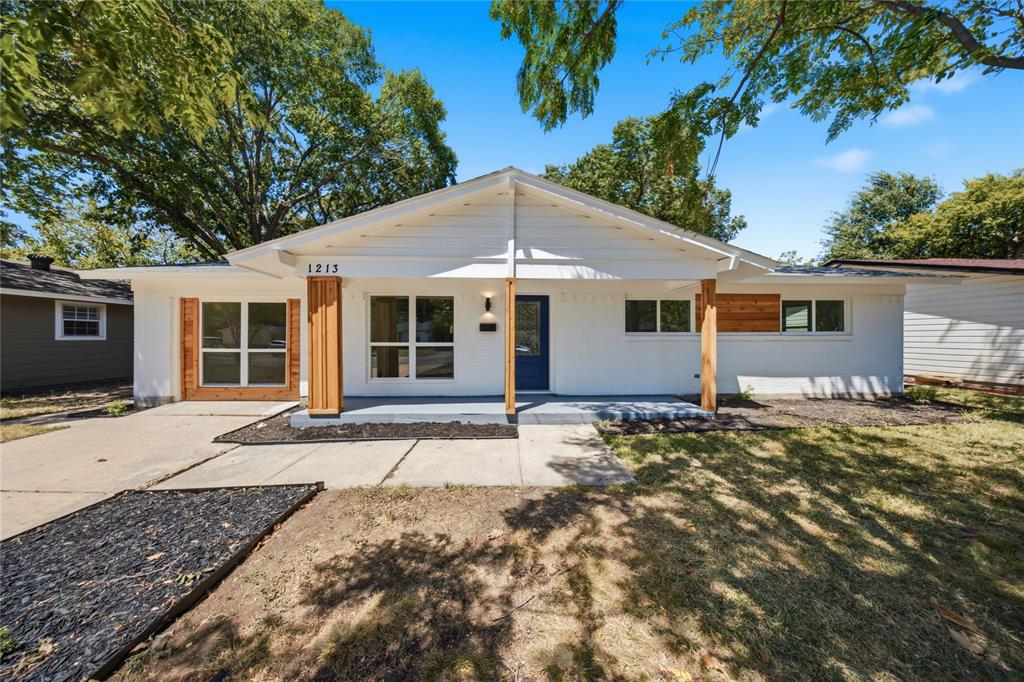 White exterior with wood-clad accents, a covered front entry, dark blue door, and large windows White exterior with wood-clad accents, a covered front entry, dark blue door, and large windows