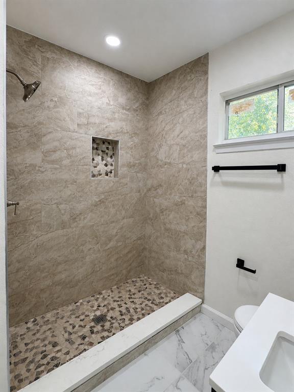 Walk-in shower with natural stone-look wall tile and a pebble floor