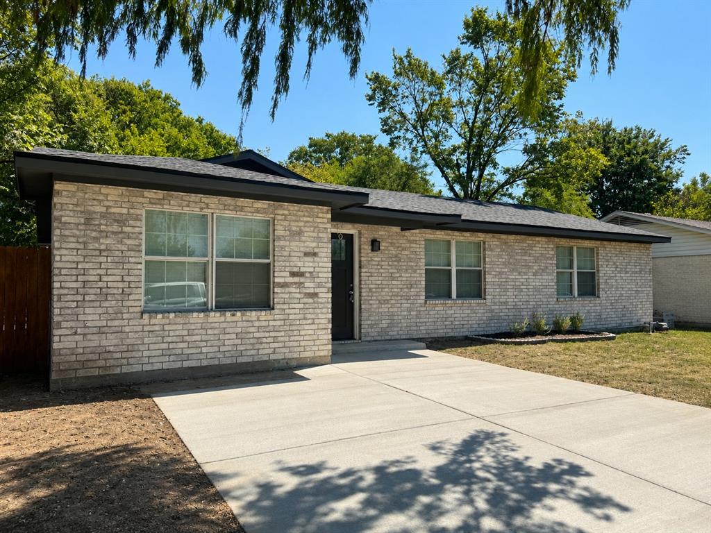 Light brick facade with dark trim, asphalt shingle roof, and a concrete driveway