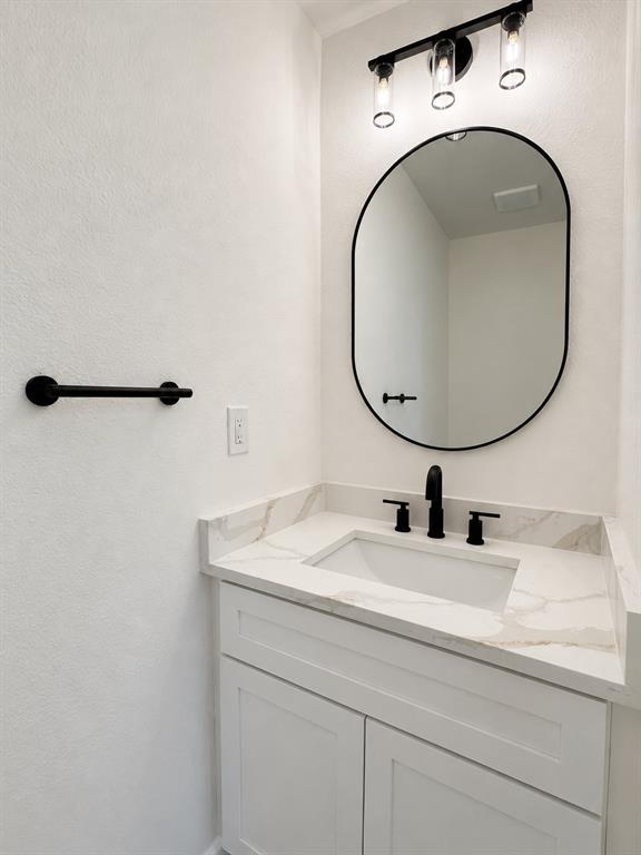 White shaker-style vanity with an integrated rectangular sink and a marble-finish countertop