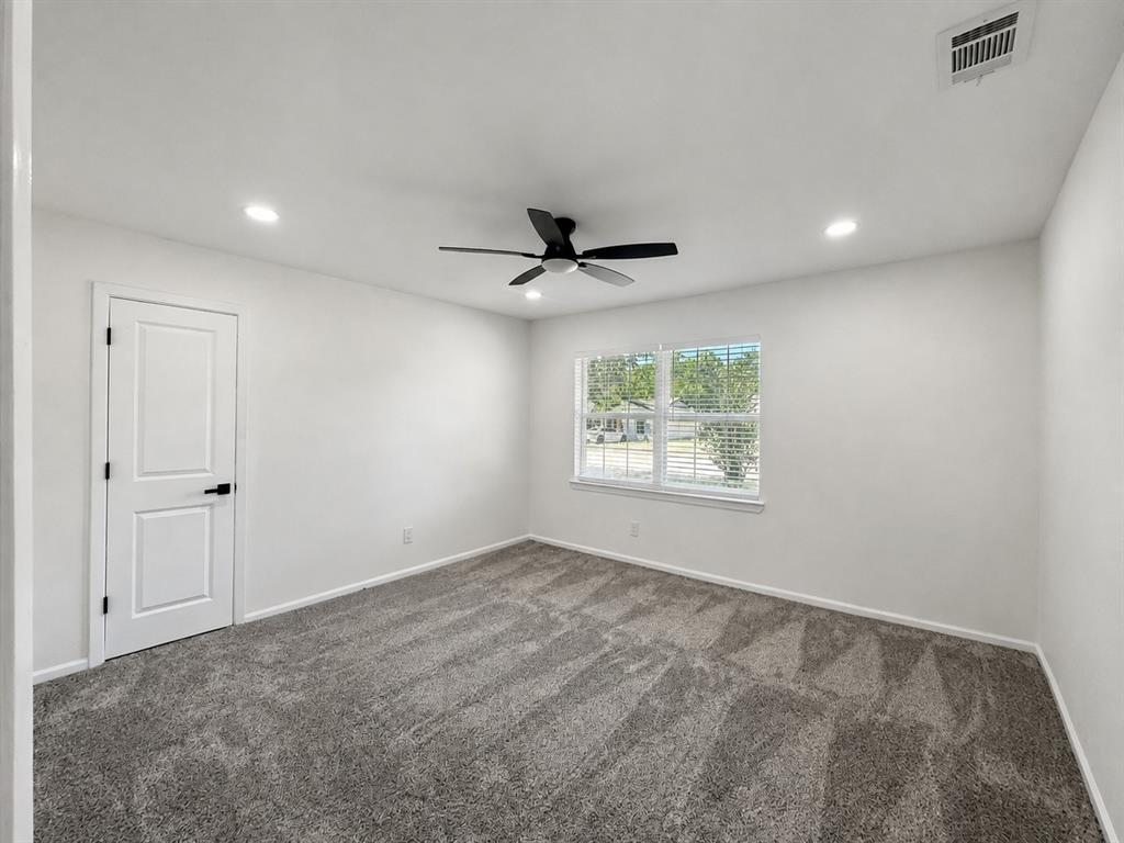 Recessed lighting, ceiling fan, white paneled door with black hardware, window with blinds, and gray carpeted flooring