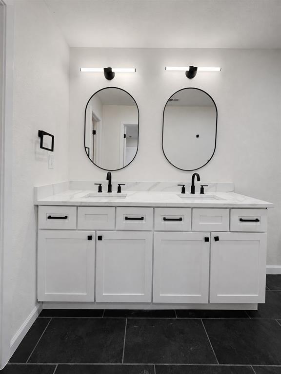 Dual vanity with white shaker-style cabinetry, matte black hardware, and a light-toned countertop