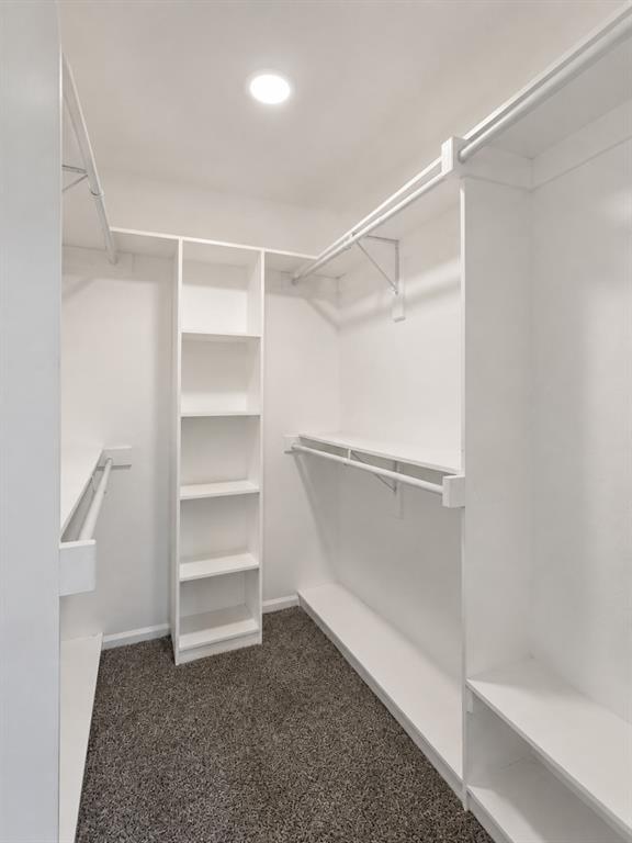 White built-in shelving, multiple hanging rods, and recessed lighting