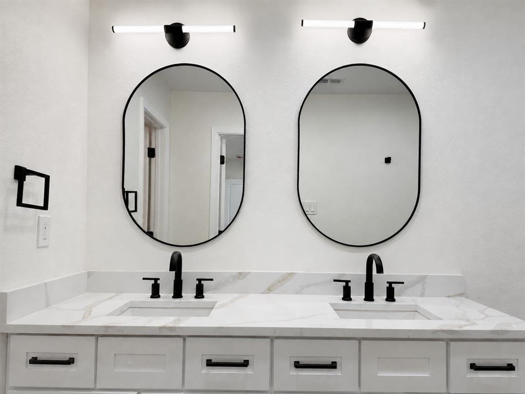 Dual vanity with white shaker-style cabinetry, white countertops featuring veining, undermount sinks, and matte black fixtures