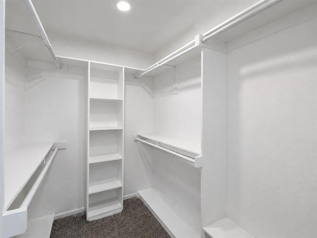 Walk-in closet featuring built-in shelving, multiple hanging rods, and recessed lighting