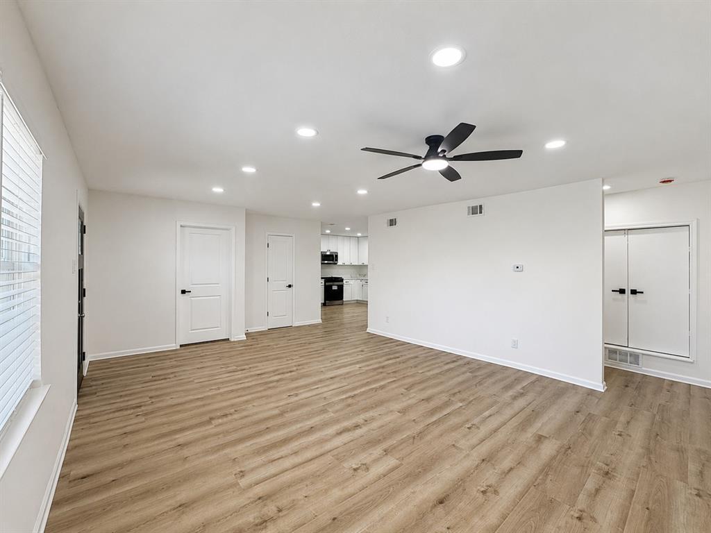 Spacious room with wood-finish flooring, recessed lighting, and a ceiling fan