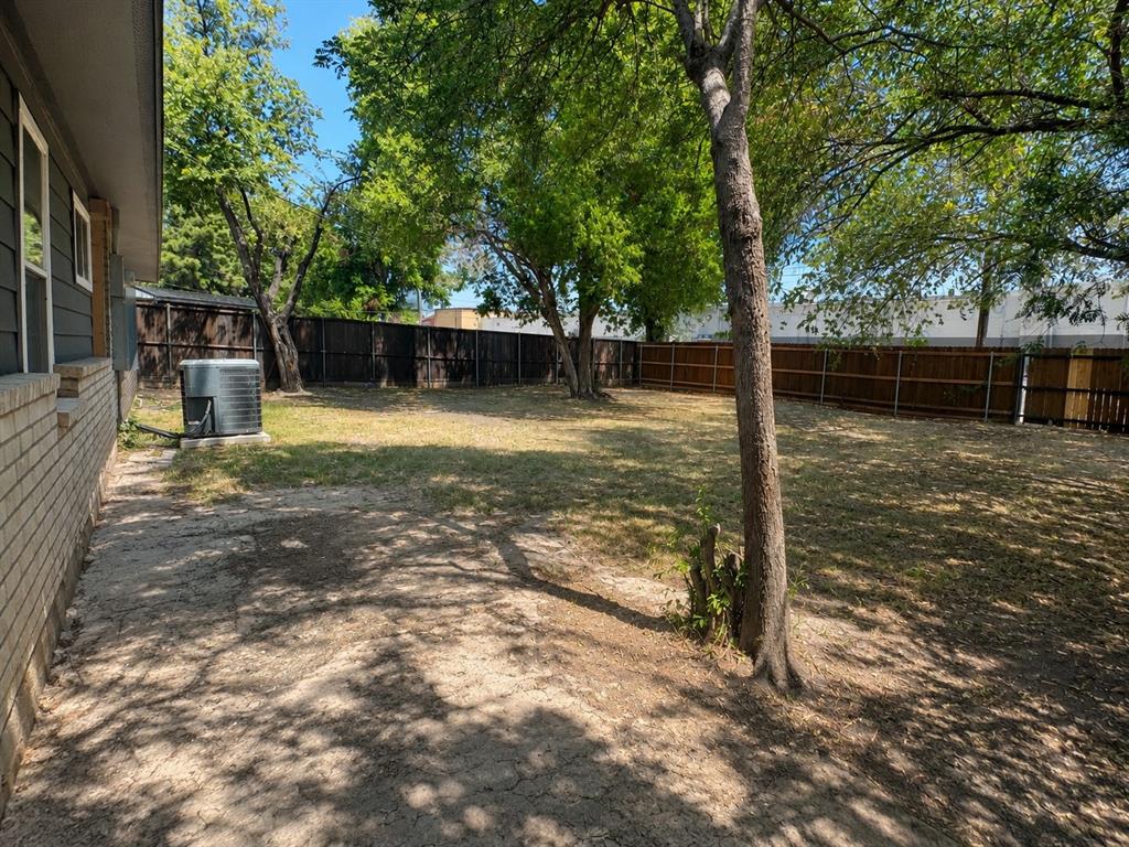 Expansive backyard with a full privacy fence, mature trees, and a brick and siding exterior