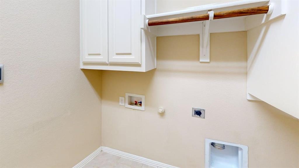Recessed appliance connections, built-in cabinetry, overhead hanging rod, and tiled flooring