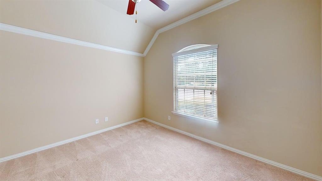Vaulted ceiling with crown molding, ceiling fan, arched window, and neutral carpeting