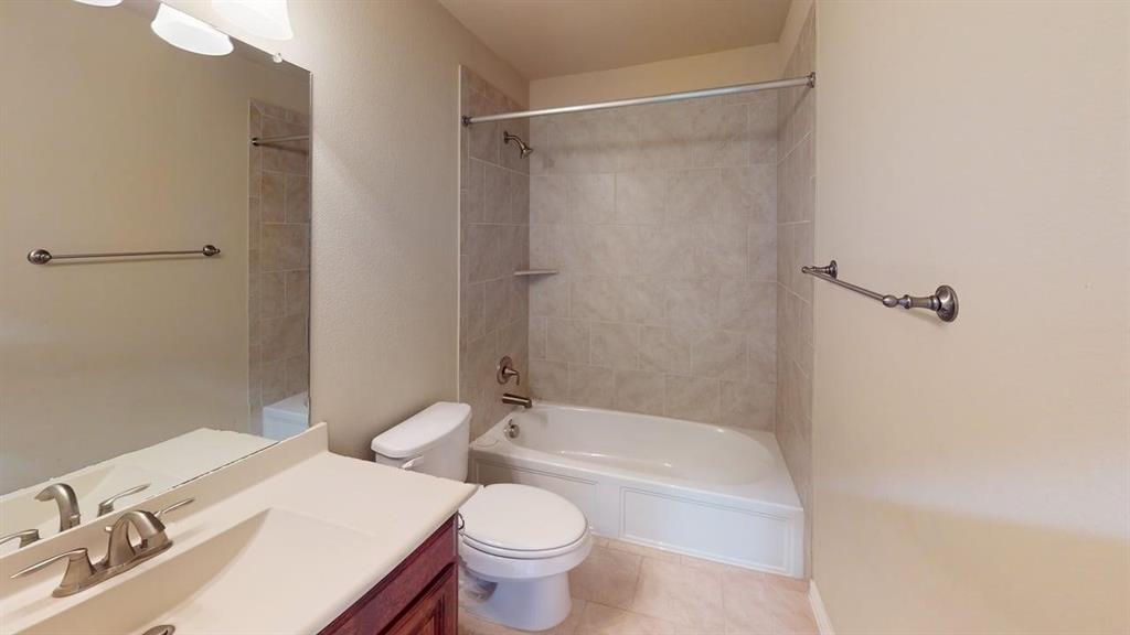 Bathroom featuring a vanity with an integrated sink, a full-width wall mirror, a tiled tub/shower combination, and ceramic tile flooring