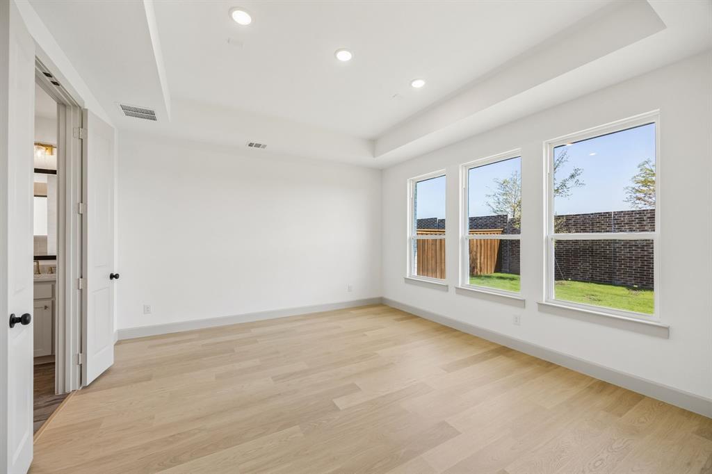 High ceilings, lovely flooring and a wall of windows create a peaceful and relaxing owner's suite.