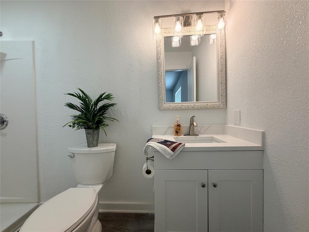 White vanity with a quartz countertop and integrated sink, framed mirror, and brushed nickel hardware
