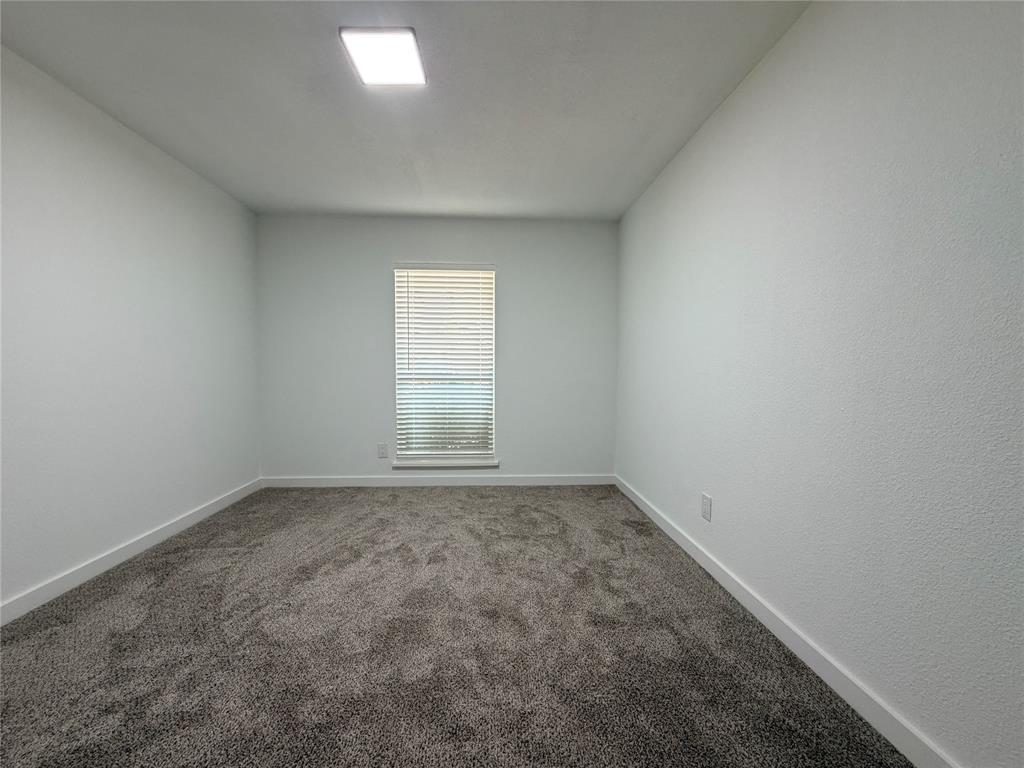 Recessed ceiling light, textured walls, window with blinds, and neutral carpeting