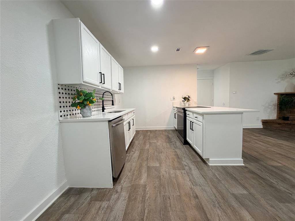 White cabinetry, dark hardware, stainless steel appliances, wood-finish flooring, and a kitchen island