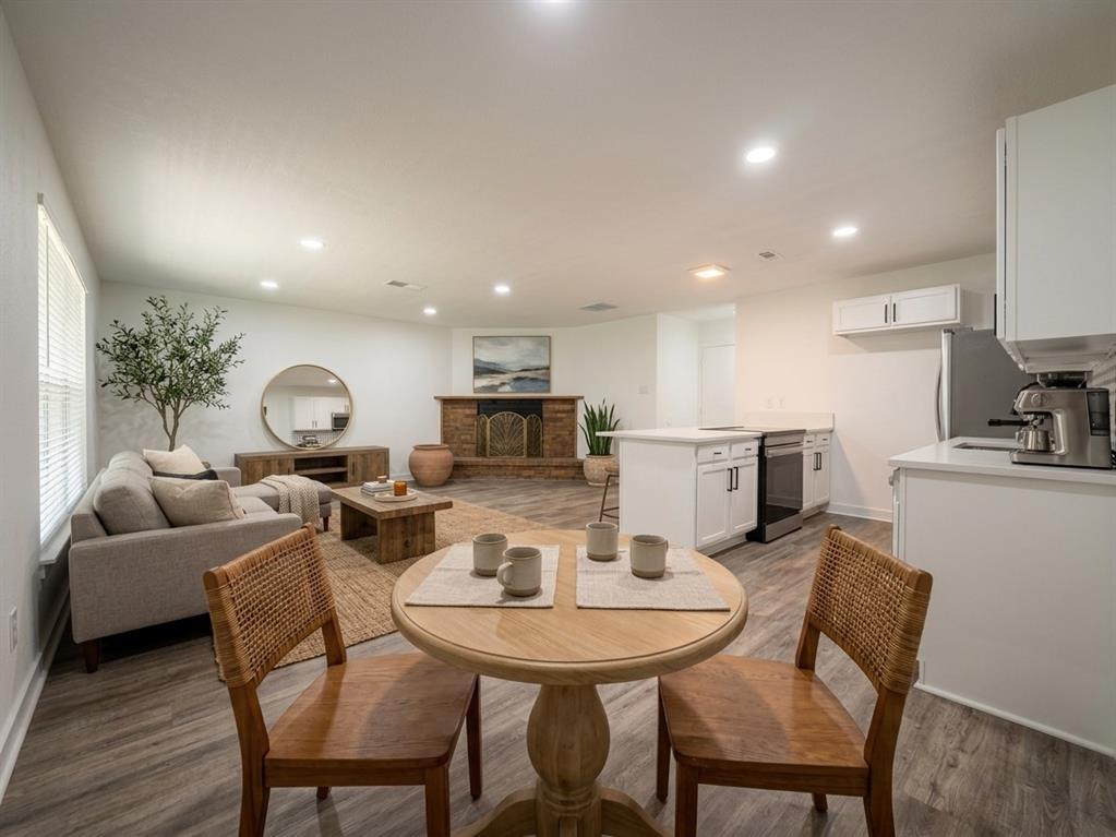 Staged-Open-concept living space featuring wood-finish flooring, recessed lighting, and a brick-faced fireplace