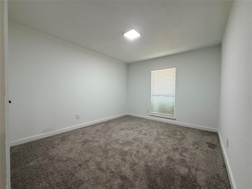 Neutral wall finishes, contemporary ceiling light fixture, window with horizontal blinds, and textured carpet flooring