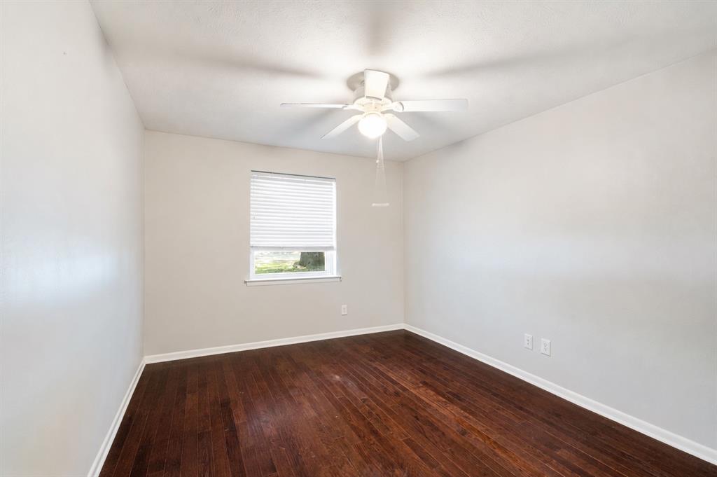 Wood-finish flooring, white walls, and a ceiling fan with integrated lighting