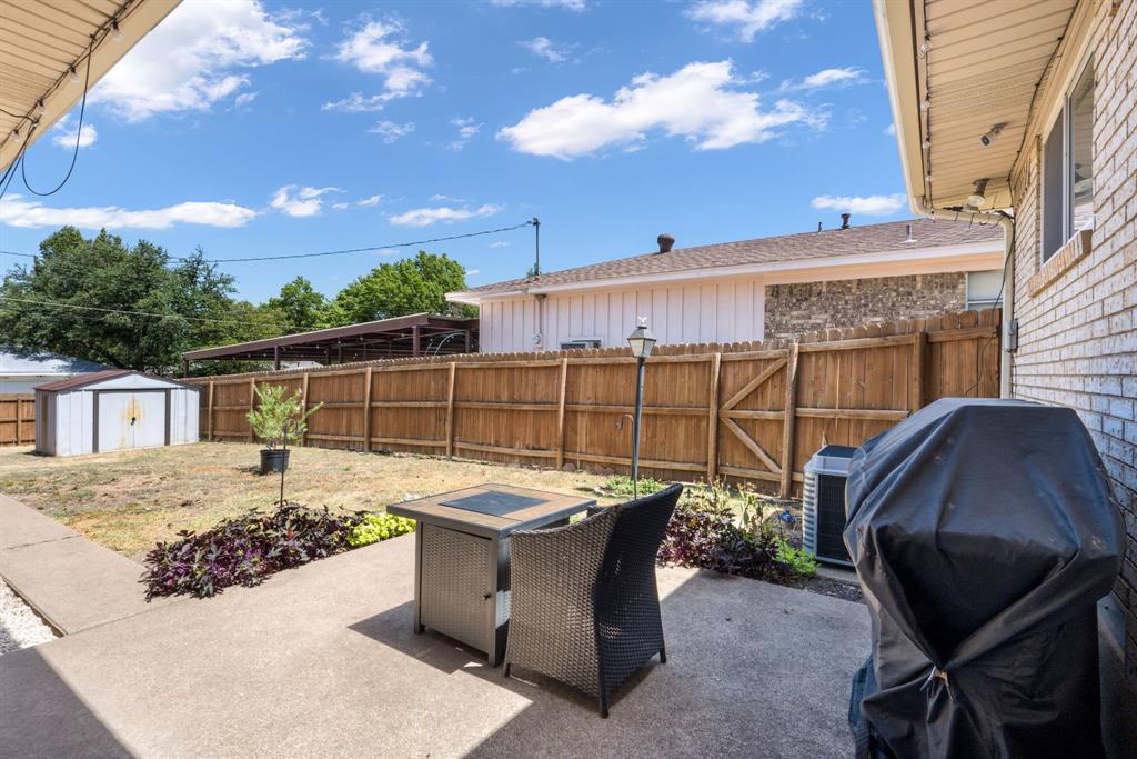 Concrete patio with an overhead awning, brick exterior, and a wooden privacy fence
