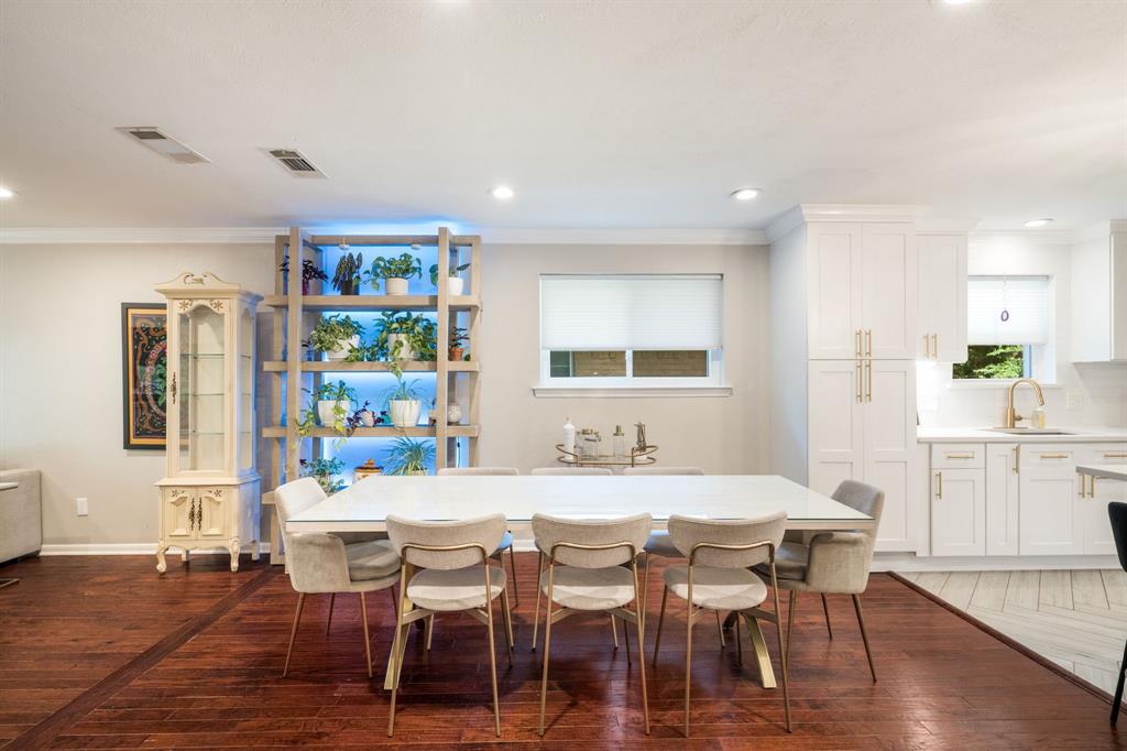 Hardwood flooring, recessed lighting, built-in shelving with integrated lighting, white shaker-style cabinetry, and subway tile backsplash