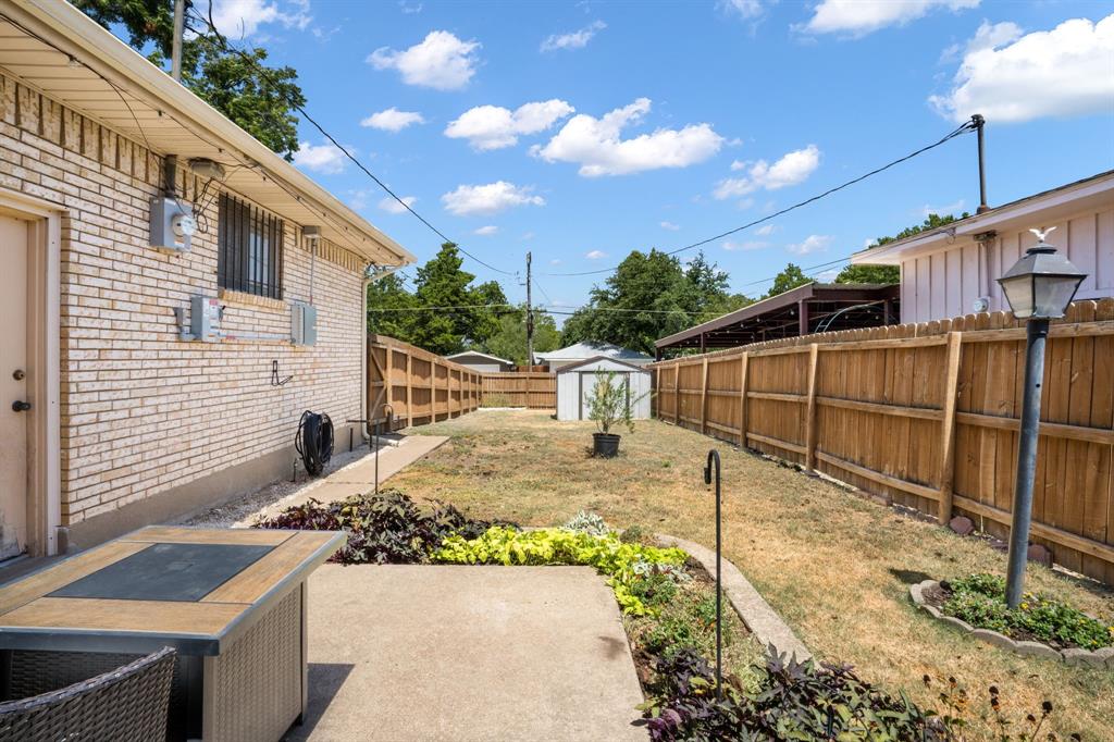 Expansive yard featuring a concrete patio, established landscaping, and wood privacy fencing