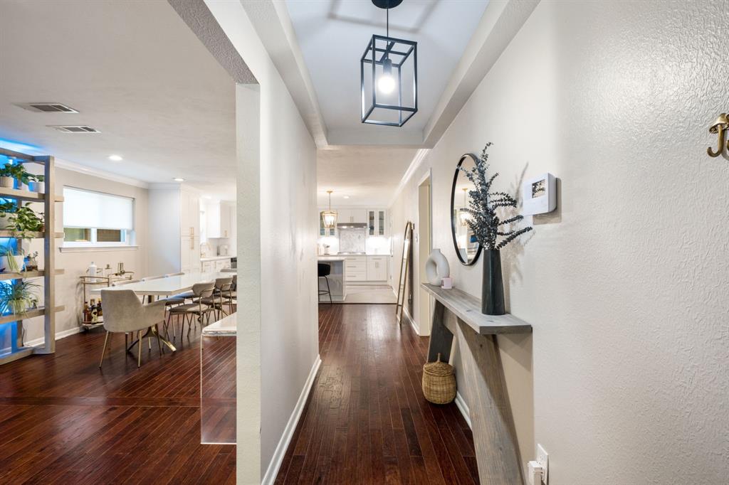 Wood-finish flooring throughout, tray ceiling with a black lantern-style pendant light, and recessed lighting