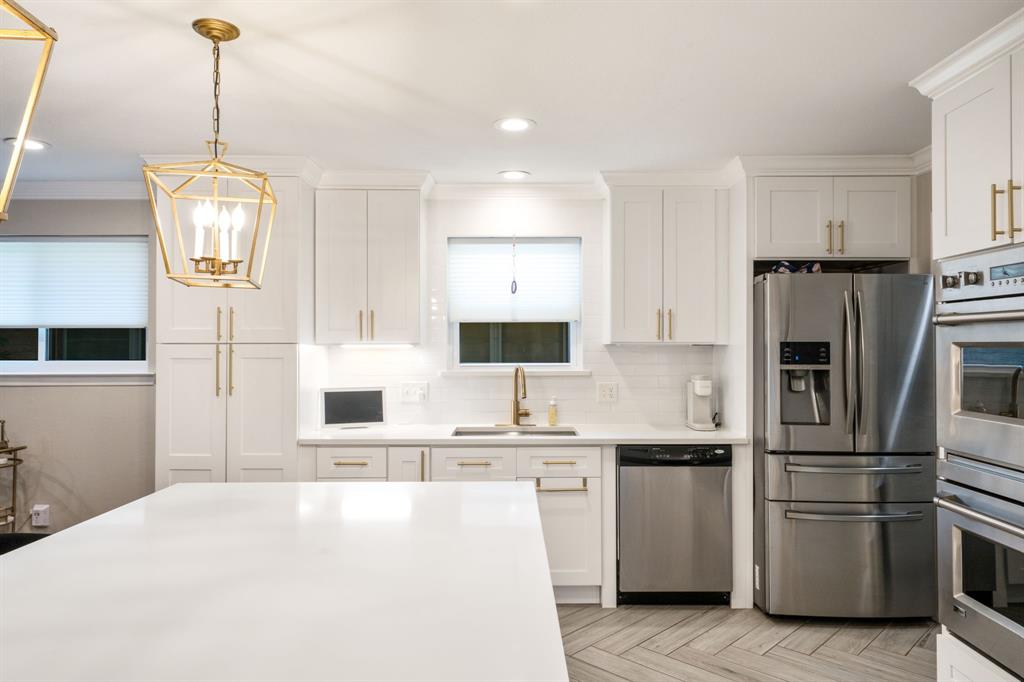 Kitchen featuring white cabinetry, stainless steel appliances, a white tile backsplash, a large kitchen island, and wood-finish flooring