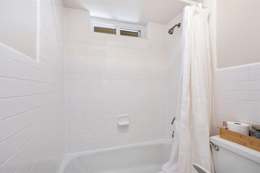 White subway tile surround, built-in bathtub, and an integrated shower head