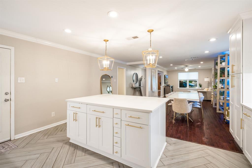 Kitchen island with white cabinetry, gold-tone hardware, and a solid surface countertop