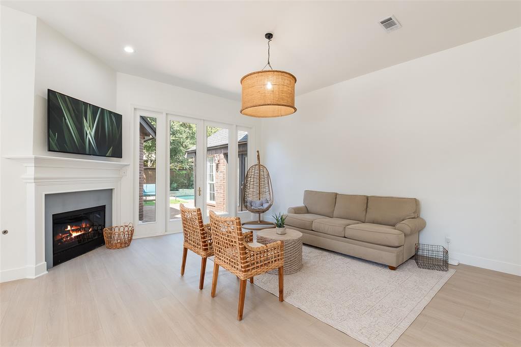 White walls, fireplace with mantel, recessed lighting, wood-finish flooring, and glass-paneled doors