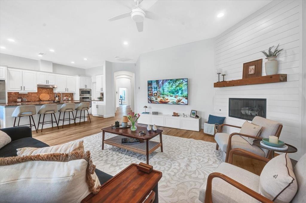 Open-concept living space featuring wood-finish flooring, a contemporary ceiling fan, and recessed lighting