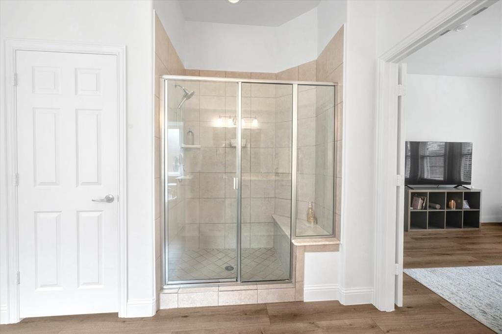 Glass-enclosed shower with a built-in bench, tiled walls, and a recessed light fixture