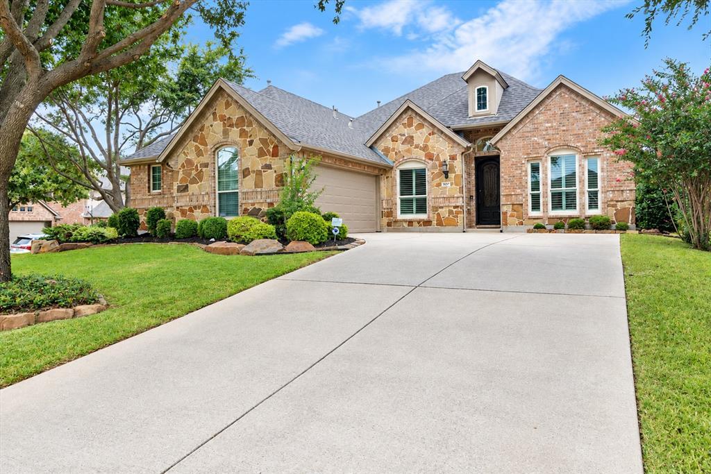 Stone and brick facade with an integrated garage, dormer window, and an arched entry