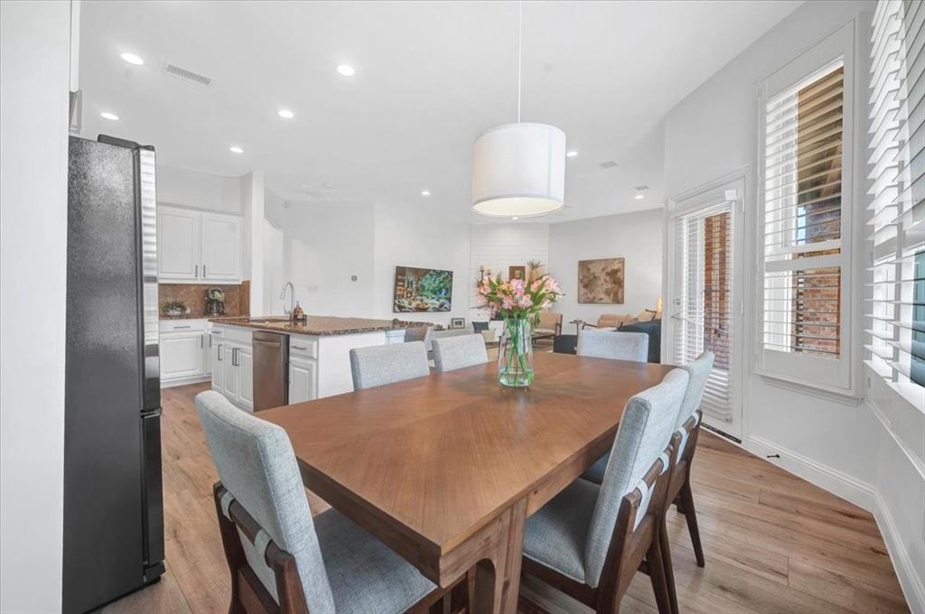 Recessed lighting throughout, wood-finish flooring, white cabinetry, island with countertop, and plantation shutters