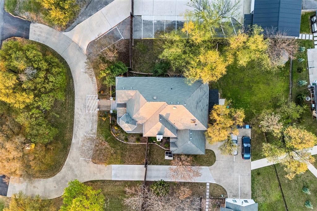 Expansive lot with mature trees, a multi-car driveway, and a well-defined paved access road