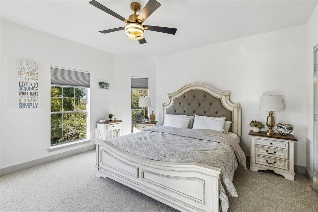 Plush carpet flooring, multiple windows with blinds, and a ceiling fan with integrated lighting