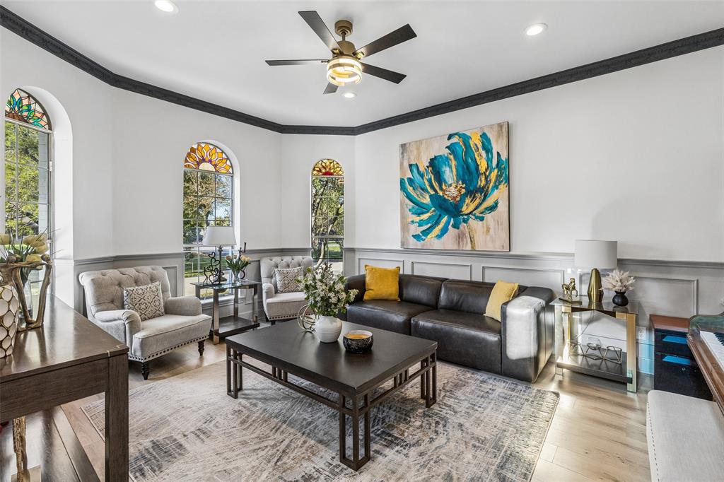 Arched windows with decorative glass, crown molding, wood-finish flooring, recessed lighting, and a ceiling fan with integrated lighting