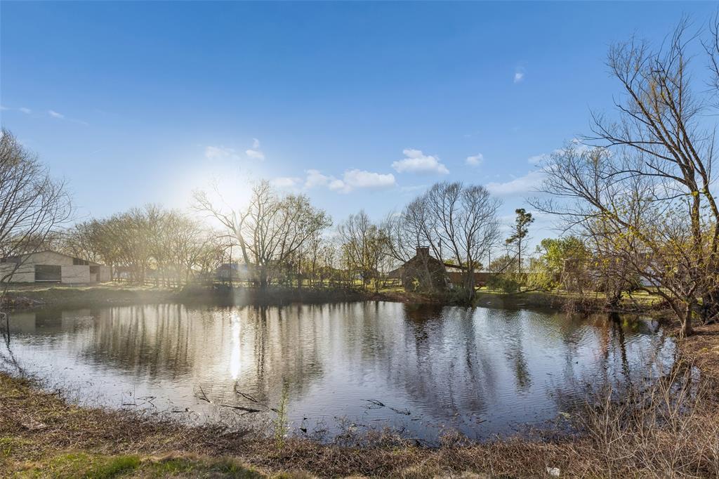 Pond with surrounding trees and a structure in the background
