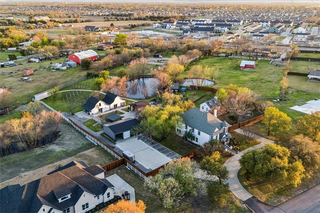 Expansive property featuring a pond, white picket fencing, and multiple outbuildings Expansive property featuring a pond, white picket fencing, and multiple outbuildings
