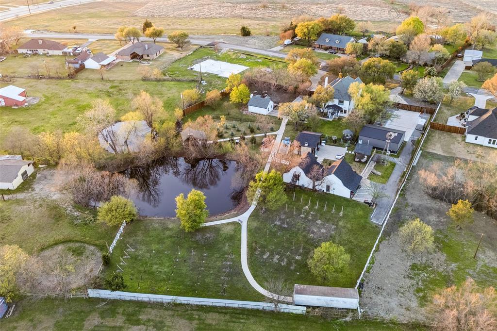 Expansive property featuring a private pond surrounded by mature trees, multiple structures, and a dedicated driveway